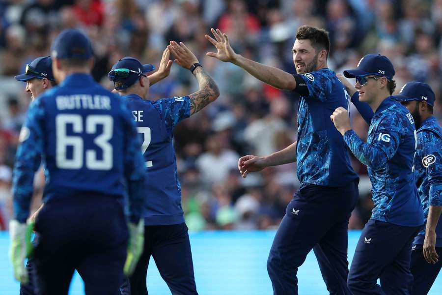 England's Jamie Overton celebrates with teammates after taking the wicket of West Indies' Roston Chase