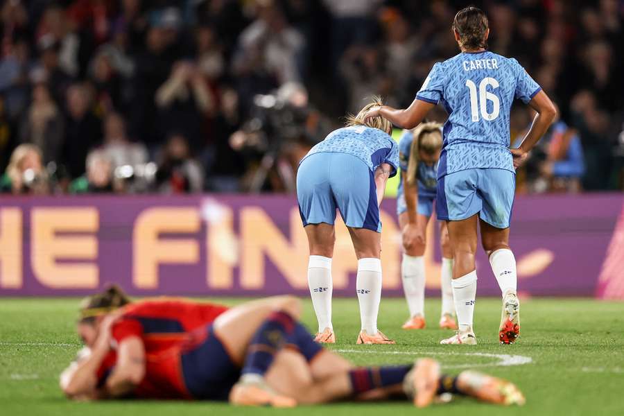 England's players react as Spain's players celebrate after winning the Women's World Cup