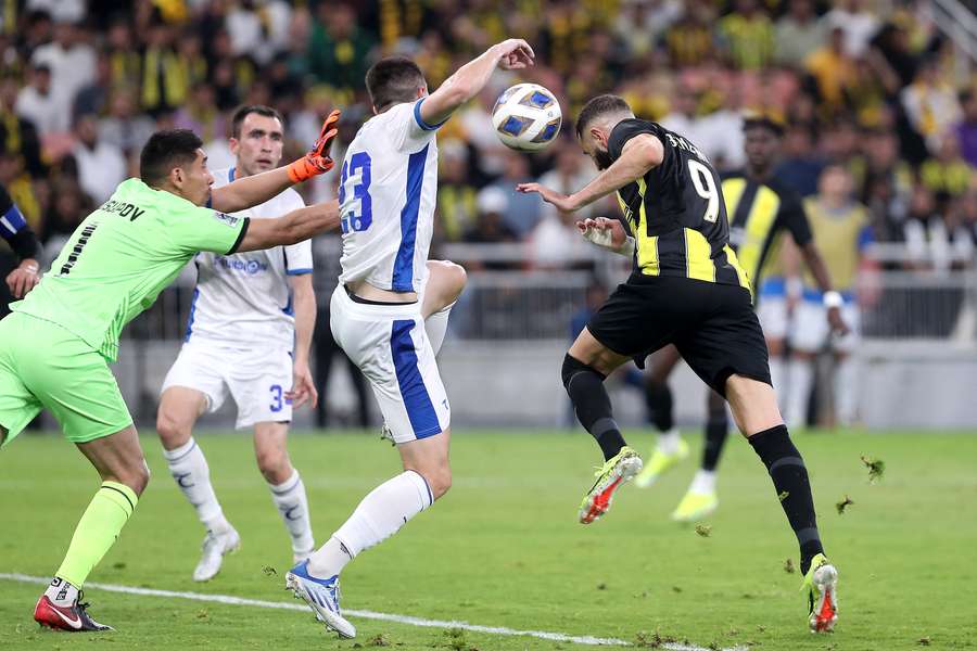Karim Benzema (R) de la Al Ittihad reușește o lovitură de cap cu  Navbahor