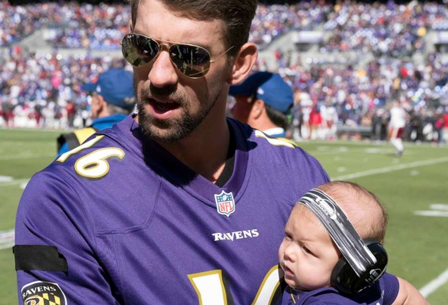 Michael Phelps e o filho Boomer foram uniformizados assistir ao jogo do Baltimore Ravens Michael Phelps e o filho Boomer foram uniformizados assistir ao jogo do Baltimore Ravens