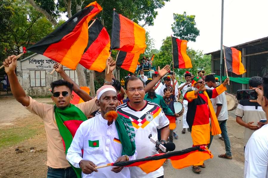 Football fans attend the unveiling of Germany's 7.5 kilometres (4.7 miles)-long national flag commisioned by Bangladeshi farmer Amjad Hossain (2L) Football fans attend the unveiling of Germany's 7.5 kilometres (4.7 miles)-long national flag commisioned by Bangladeshi farmer Amjad Hossain (2L)