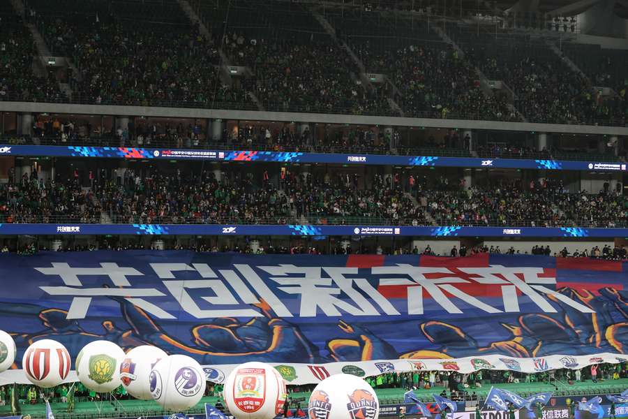 Fans cheer during the Chinese Super League football match between Beijing Guoan FC and Meizhou Hakka FC
