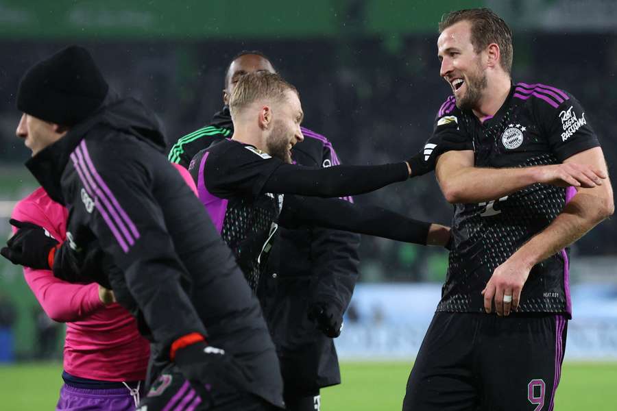 Bayern Munich's English forward #09 Harry Kane (R) and teammates celebrate with fans after their victory