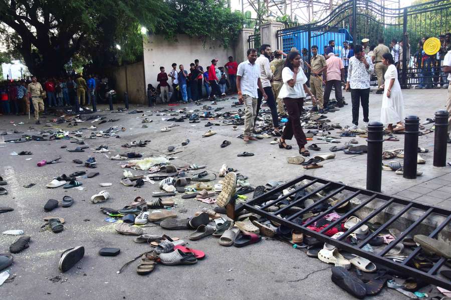 Fans stand next to abandonned shoes and a fallen barrier following a stampede during Bengaluru's IPL celebrations