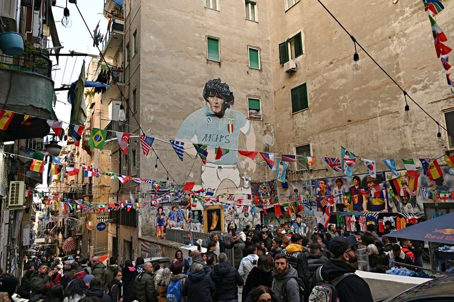 People gather in front of a mural of late Argentine football legend Diego Maradona in Naples