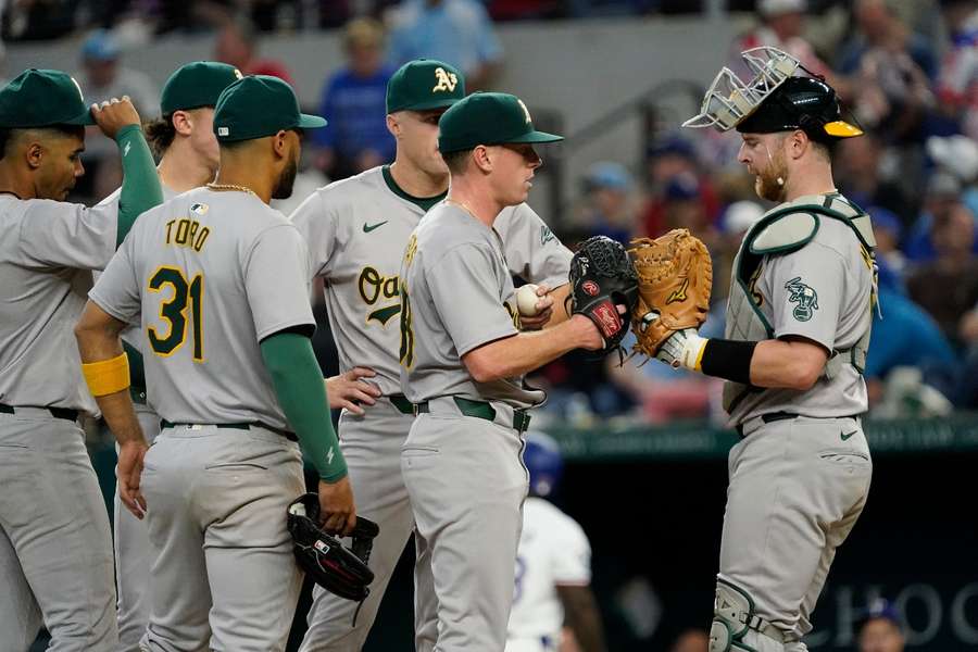 Oakland Athletics pitcher JP Sears bumps gloves with catcher Kyle McCann after giving up a single against the Texas Rangers