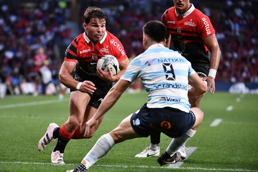 Antoine Dupont (L) runs with the ball 