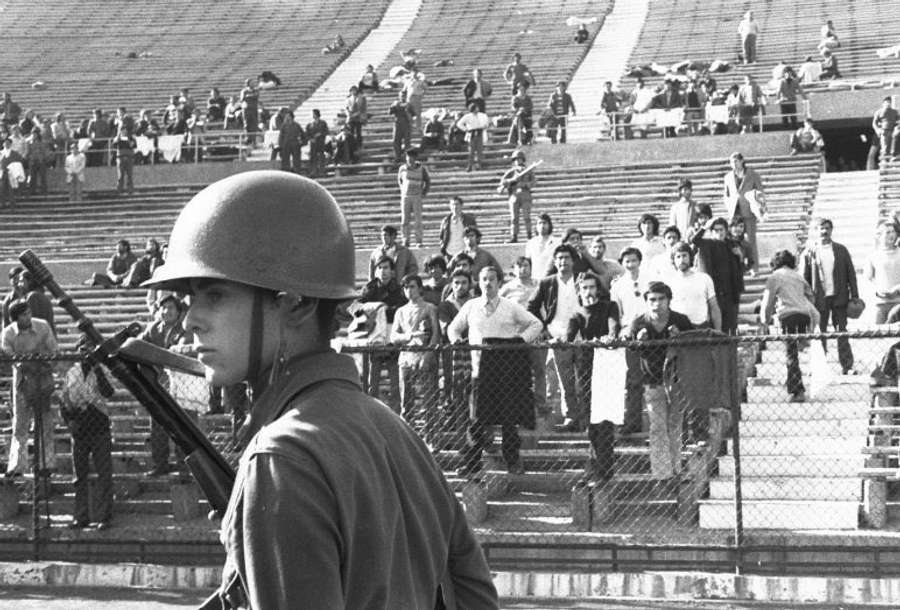 Imagem dos presos sob o olhar e a arma de um militar