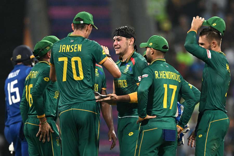 South Africa's Gerald Coetzee (C) celebrates with teammates after taking the wicket of England's captain Jos Buttler