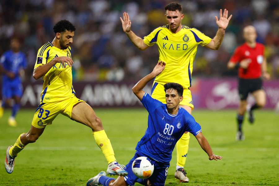 Esteghlal FC's Mohammad Hossein Eslami in action with Al Nassr's Aymeric Laporte and Salem Al Najdi