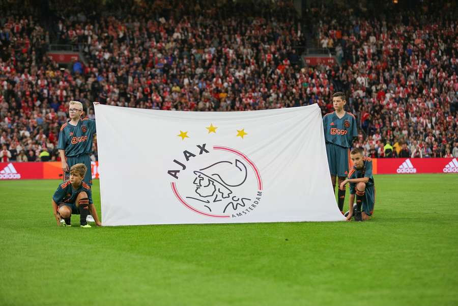 De jeunes supporters brandissent le logo de l'Ajax.