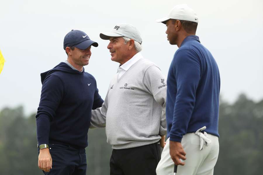 Rory McIlroy of Northern Ireland, Fred Couples of the United States and Tiger Woods of the United States talk on the 18th green