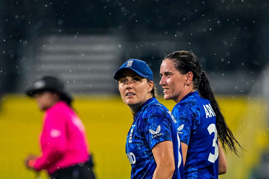 England's Em Arlott (R) and captain Nat Sciver-Brunt walk back to the pavilion as rain halts play during the Women's World Cup match against Pakistan