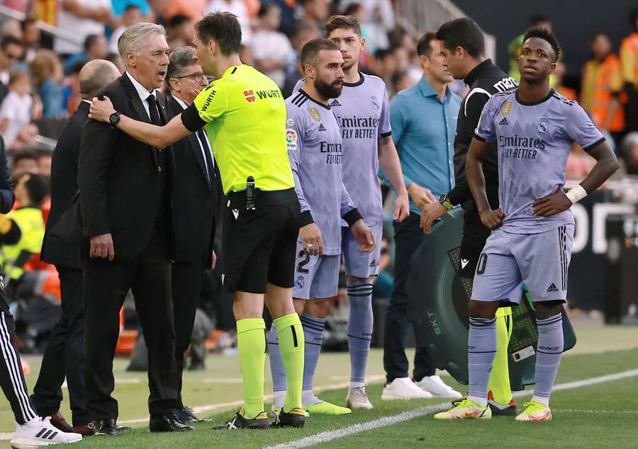 Real Madrid's Italian coach Carlo Ancelotti (L) talks with Spanish referee De Burgos Bengoetxea next to Real Madrid's Brazilian forward Vinicius Junior