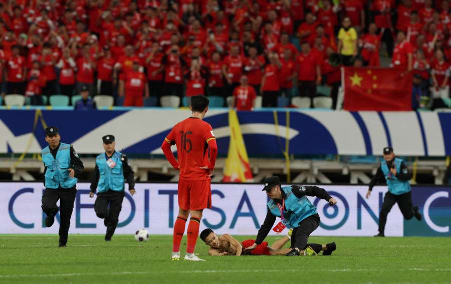 Security officials stop the pitch invader after he ran onto the pitch during the match