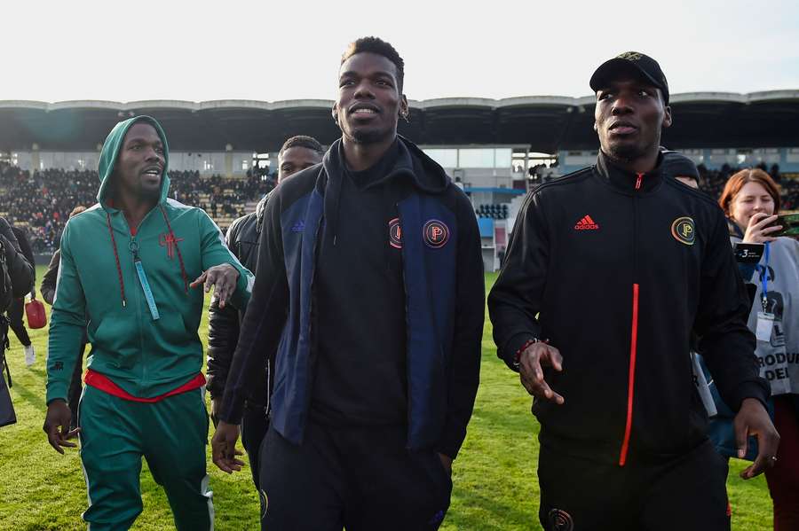 Paul Pogba (C) și frații săi Mathias Pogba (L) și Florentin Pogba pășesc pe teren înainte de meciul de fotbal dintre All Star France și Guineea