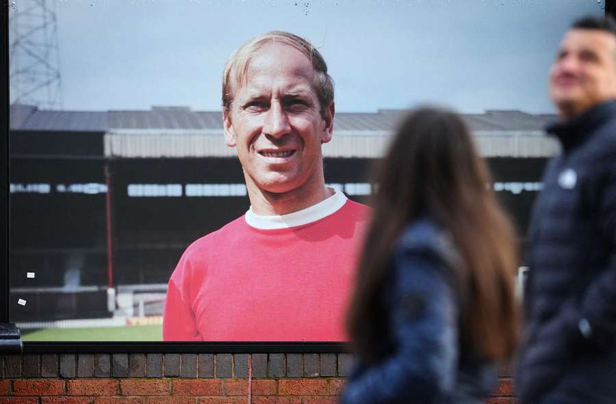 People walk past an image of former Manchester United player Bobby Charlton outside of Old Trafford