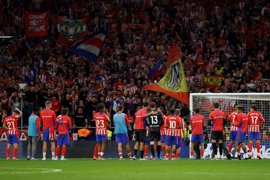 Los jugadores del Atlético saludan a sus aficionados en el fondo donde se lanzaron mecheros a Courtois