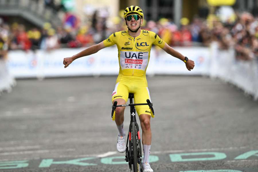 Slovenian rider Tadej Pogacar wearing the overall leader's yellow jersey cycles to the finish line to win the 14th stage