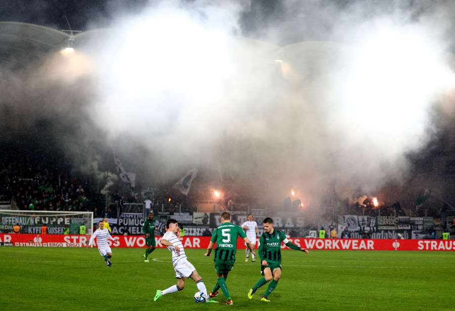 Monchengladbach's Marvin Friedrich in action as fans are seen with flares in the stands
