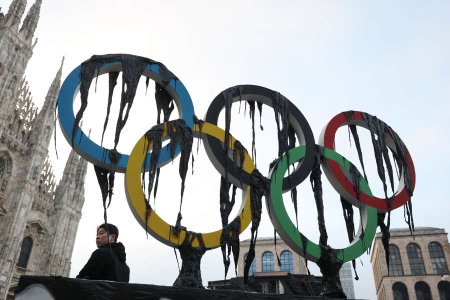 A man looks on next to a large installation unveiled by environmental activists from Greenpeace as the Olympic torch arrives in Milan