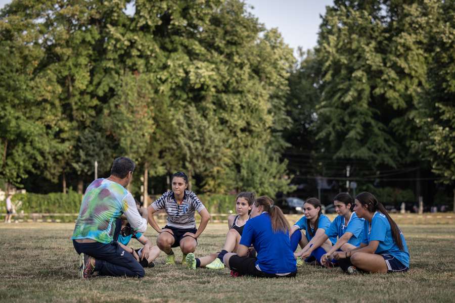 Team members listen to coach Nicolae Ungureanu (L) during a training session