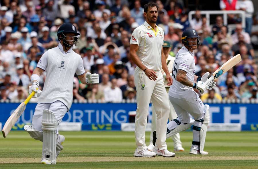 Australia's Mitchell Starc (C) watches as England's Ben Duckett (L) and England's captain Ben Stokes add runs on day five