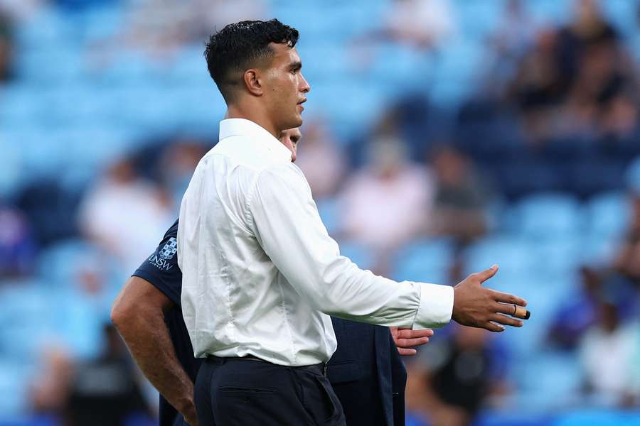 A suited up Joseph Suaalii watches his teammates warm up during their most recent match.