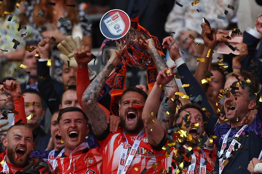 Sonny Bradley lifts the trophy as Luton's players celebrate