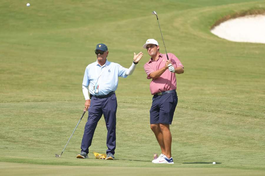 Scottie Scheffler (R) chips with coach Randy Smith during a practice round ahead of the 2022 Presidents Cup.