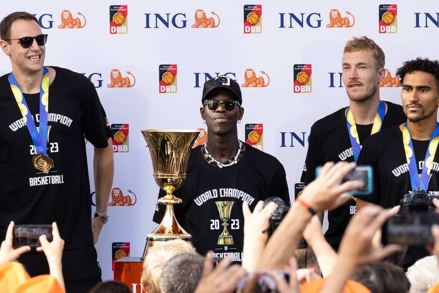 Kapitän Dennis Schröder (M.) und die WM-Trophäe 2023.