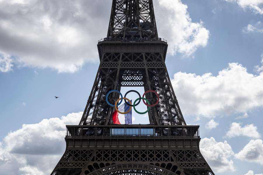 A French national flag flutters on the Eiffel Tower behind the Olympic rings 