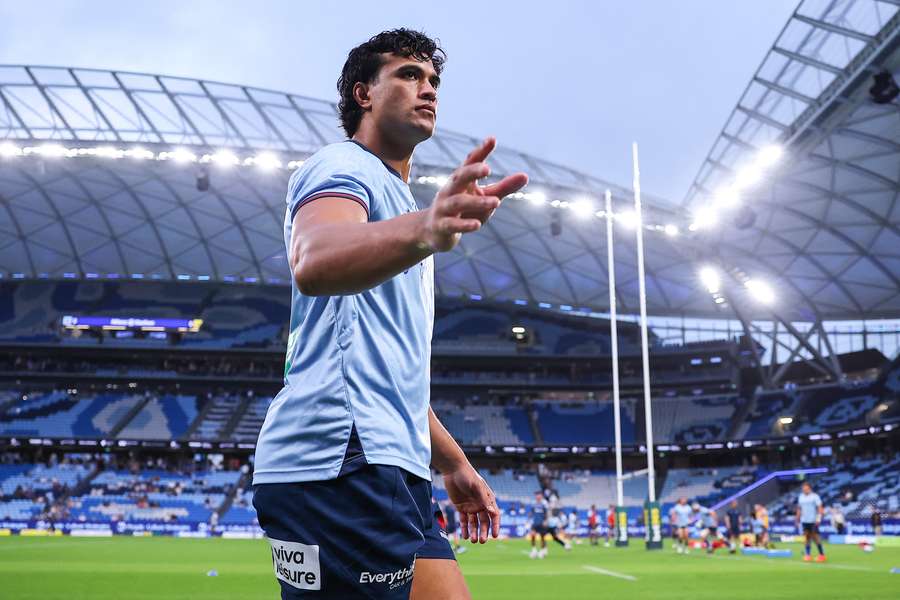 A happier Joseph Suaalii waves to fans during pre-game warm-up.