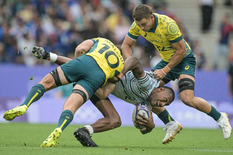 Joseva Talacolo (C) van Fiji wordt getackeld door Nick Malouf (L) en Nathan Lawson (R) van Australië tijdens de halve finale voor mannen.