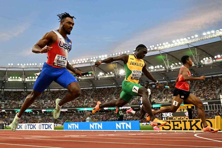 USA's JT Smith, Jamaica's Rohan Watson and Japan's Abdul Hakim Sani Brown cross the finish line in the men's 4x100m relay heats