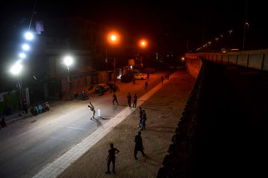 Dozens of young Pakistani men chase taped-up tennis balls zipping through the night air