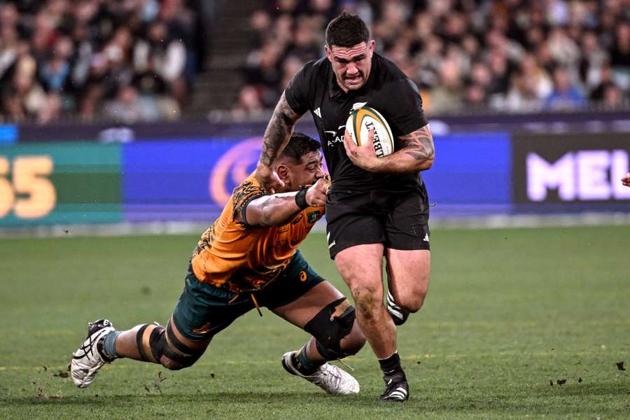 New Zealand's Codie Taylor (C) breaks through the Australian defence in the Rugby Championship