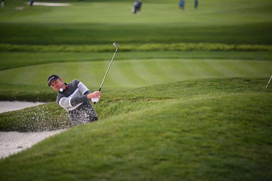 Justin Rose of England plays a shot from a bunker