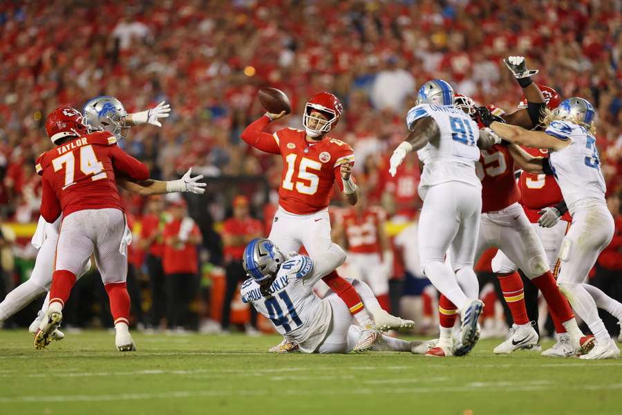 Patrick Mahomes probeert een bal te gooien terwijl James Houston van de Lions aan zijn benen hangt