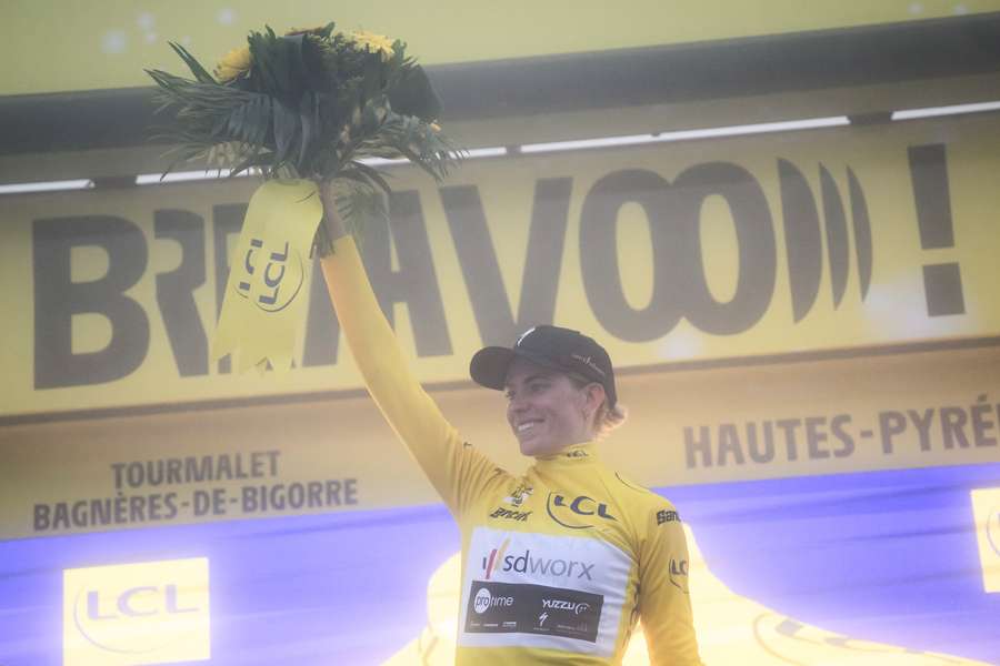 Team SD Worx's Demi Vollering celebrates on the podium as she wears the overall leader's yellow jersey after the seventh stage