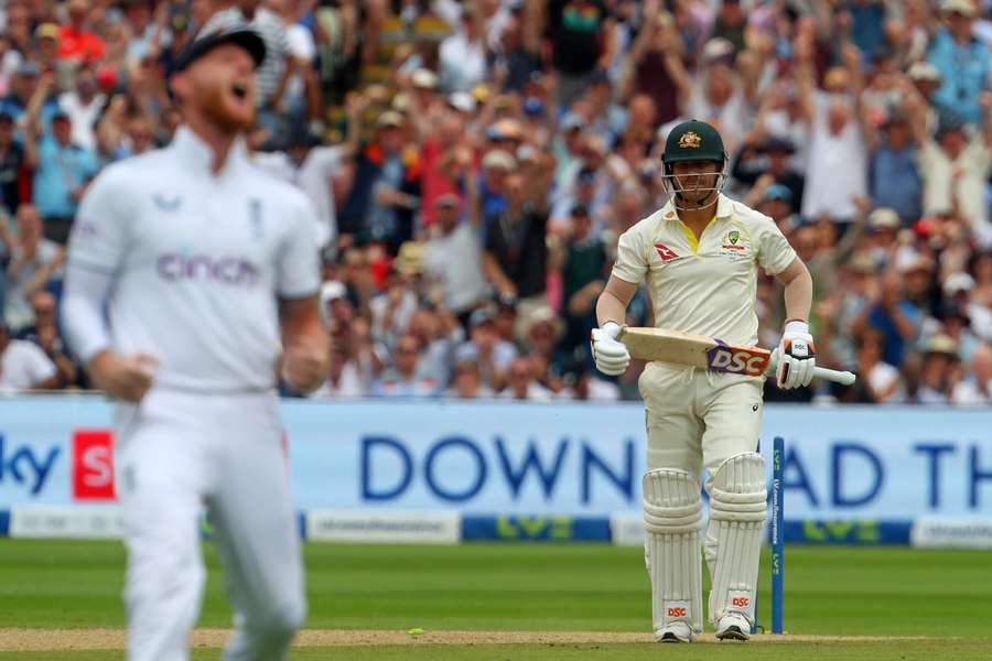England's captain Ben Stokes (L) celebrates as Australia's David Warner (R) reacts after being bowled by England's Stuart Broad