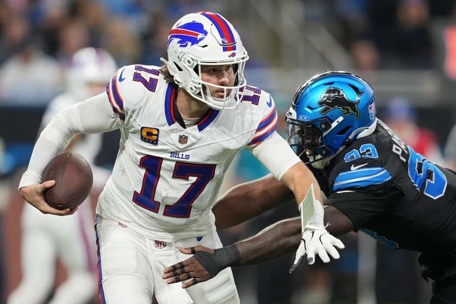 Josh Allen de los Buffalo Bills corre con el balón mientras es perseguido por Josh Paschal de los Detroit Lions.