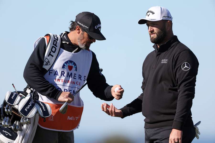 Jon Rahm of Spain talks with his caddie on the 11th green