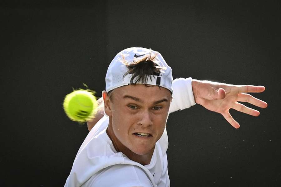 Denmark's Holger Rune eyes the ball as he returns the ball to Britain's George Loffhagen