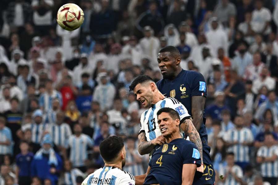 Argentina's defender Cristian Romero heads the ball as he is challenged by France's defender Raphael Varane during the Qatar 2022 World Cup final