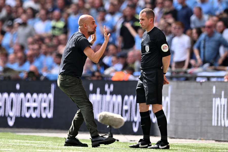 Manchester City manager Pep Guardiola (L) gestures to fourth official Peter Bankes (R)