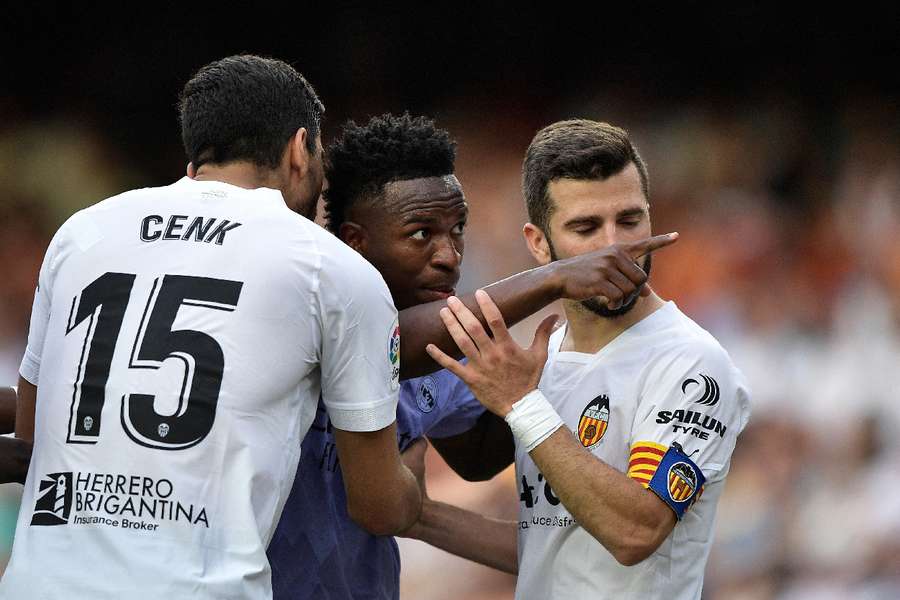 Vinicius Jr gestures towards a fan as Valencia's Jose Gaya and Cenk Ozkacar attempt to restrain him