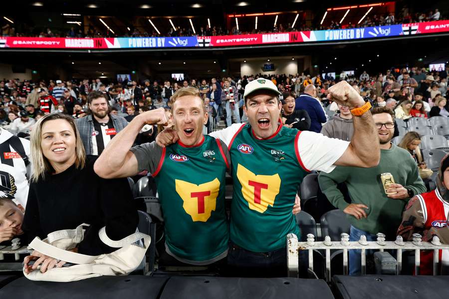 Two supporters wear the prospective Tasmania AFL guernseys at a game between Collingwood and St Kilda.
