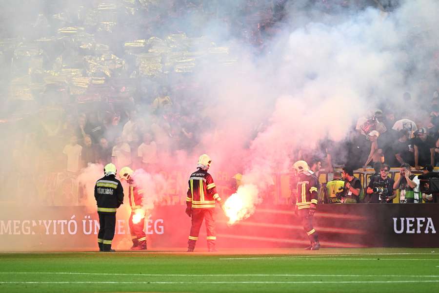 Firefighters remove flares from the pitch