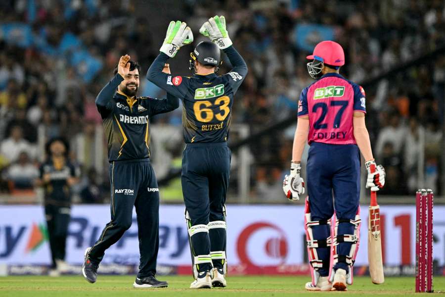 Gujarat Titans' Rashid Khan (left) celebrates with wicketkeeper Jos Buttler after taking the wicket of Rajasthan Royals' Shubham Dubey